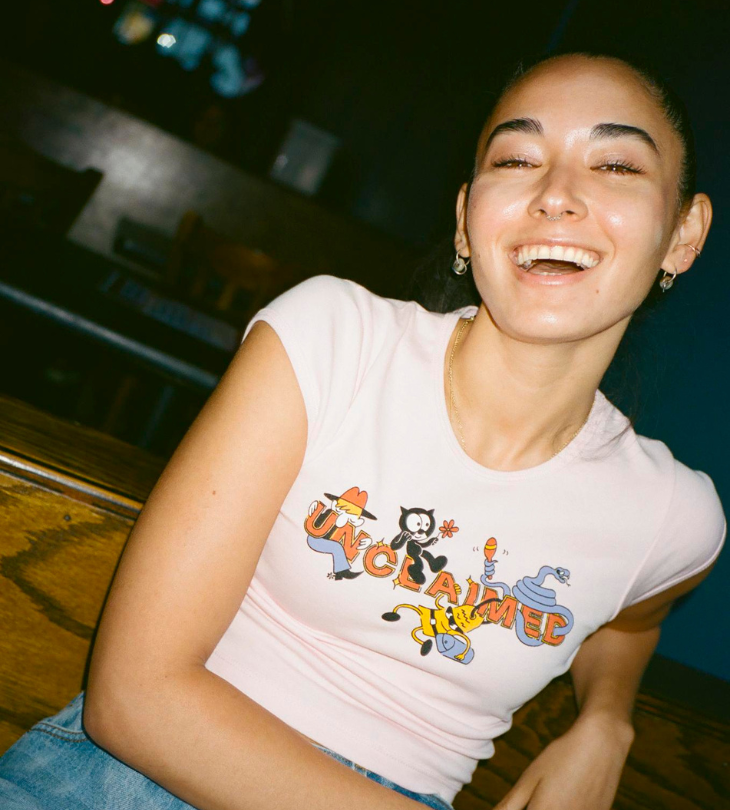 a woman laughing wearing a cropped t-shirt sitting at a bar