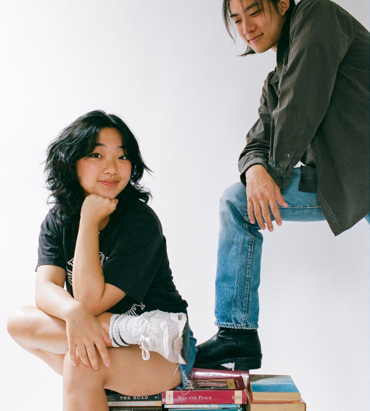 2 people posing on top of books 