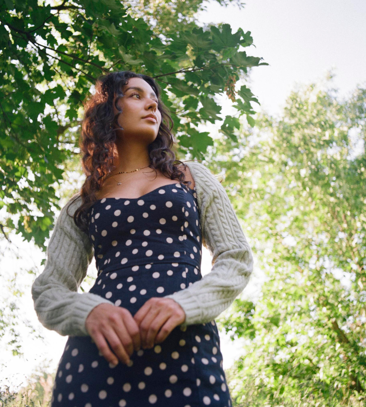 a woman in a navy polka dot dress in the forest