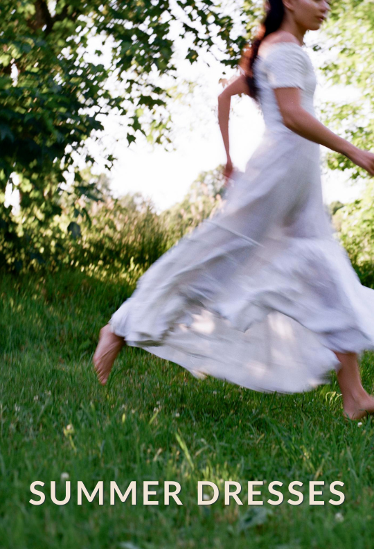 a woman running through the woods wearing a white dress with caption "Summer Dresses" 